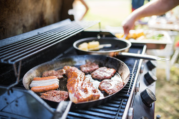 Meat and sausages on the grill. Garden party outside in the backyard.