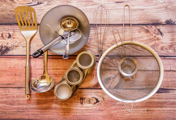 Various metal kitchen utensils on wooden background, top view