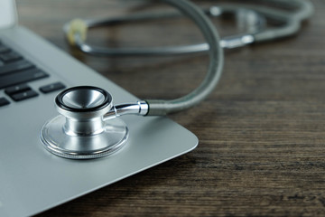 Doctor desk table with stethoscope and laptop on wooden table, medical workspace office..