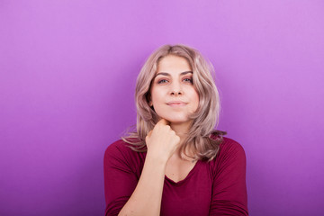 Happy smiling young blonde woman portrait on purple background