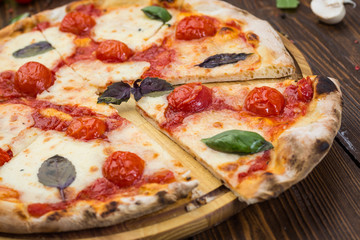 rustic italian pizza Margarita with mozzarella, cherry tomatoes and basil leaves on wooden background