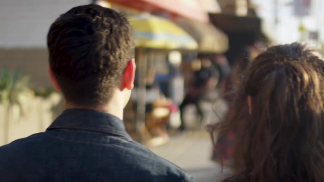 Happy Couple Explore Venice Beach Together, They Talk/Walk Along Sidewalk Past Shops And Restaurants (Slow Motion)