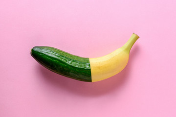 Сonnected banana and cucumber on pink background. Minimal fruit concept.