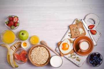 Obraz na płótnie Canvas Breakfast served with coffee, orange juice, oat cereal, milk, fruits, eggs and toast. Balanced diet. Morning sweet and savory meal, food background. overhead, horizontal