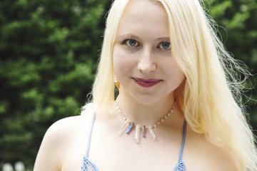 Portrait of beautiful young woman with blond hair, blue eyes, and crystal quartz necklace