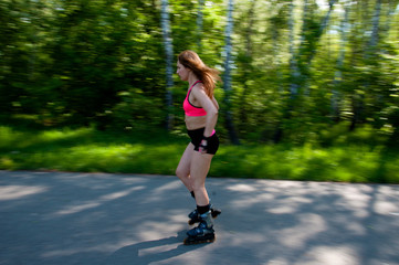Roller skating woman in park rollerblading on inline skates. Beautiful woman learns to roller skate...