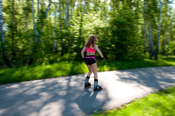 Roller skating woman in park rollerblading on inline skates. Beautiful woman learns to roller skate...