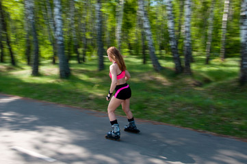 Roller skating woman in park rollerblading on inline skates. Beautiful woman learns to roller skate...
