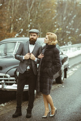 Escort of girl by security. Couple in love on romantic date. Bearded man and sexy woman in fur coat. Travel and business trip or hitch hiking. Retro collection car and auto repair by mechanic driver.