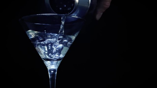  Close up of a martini drink poured into a glass. A fresh oil is put in the glass.
