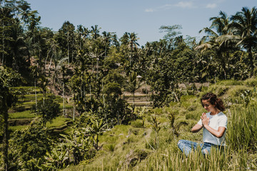 Young happy woman enjoying and meditating with the lovely view of the rice terrace in Bali, Indonesia. Sunny, relaxed day in Tegalalang. Travel photograph. Lifestyle.