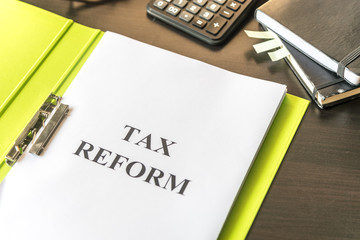 Folder and documents about Tax Reform with calculator and glasses on table background.
