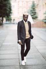 Full length portrait of young african businessman walking in the city street