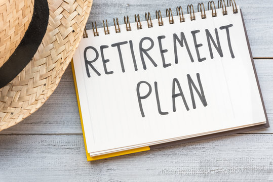 Retirement plan hand written in a note, concept of starting senior investment pension retirement life with hat on white wooden background. Happy vacation retire.
