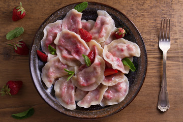 Dumplings, filled with strawberries. Pierogi, varenyky, vareniki, pyrohy - dumplings with filling. View from above, top, overhead