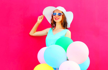 Elegant woman and air colorful balloons is having fun on a pink background