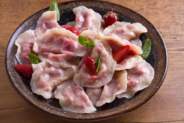 Dumplings, filled with strawberries. Pierogi, varenyky, vareniki, pyrohy - dumplings with filling. View from above, top, overhead