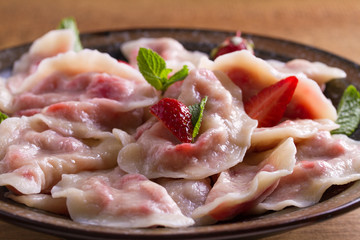 Dumplings, filled with strawberries. Pierogi, varenyky, vareniki, pyrohy - dumplings with filling. View from above, top, overhead