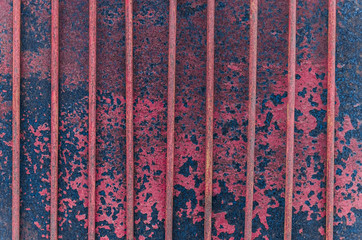 A background of an old rusty fence made of metal sheet and a grille. On the texture of the remains of paint.