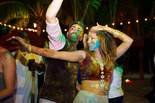 Hindu man and woman covered with colorful fye dance on the beach