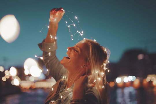 Happy young blonde woman garland fairy lights