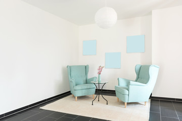 Detail of two turquoise armchairs in empty apartment
