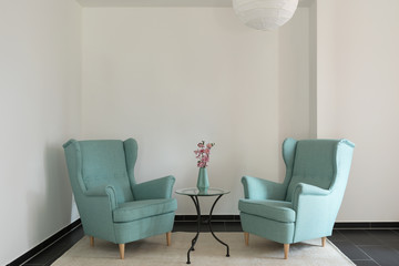 Detail of two turquoise armchairs in empty apartment