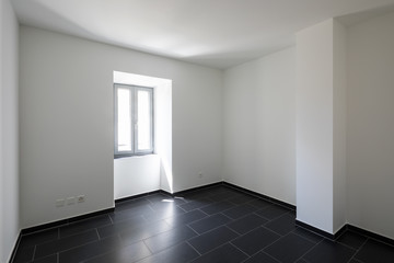 Empty room with white walls and black tiles