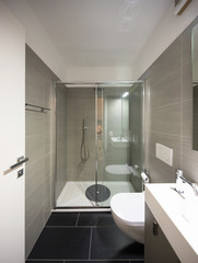 Modern bathroom with large brown tiles and large mirror