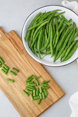 Freshly Picked Green Beans in a White Bowl, Some Cut on Cutting Board, all on Gray Background