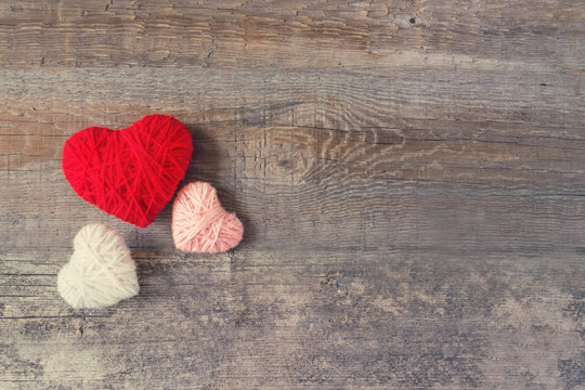Three Red, white, pink thread heart on dark wooden vintage background. Handmade pretty heart. Love, romance, Valentines day, wedding, honeymoon, DIY concept. Selective focus