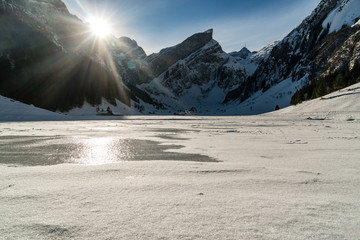 frozen lake with small village, swiss mountains