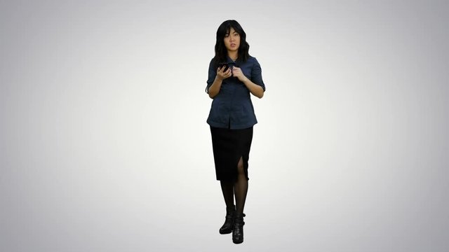 Young asian women standing with smartphone and talking to a camera on white background
