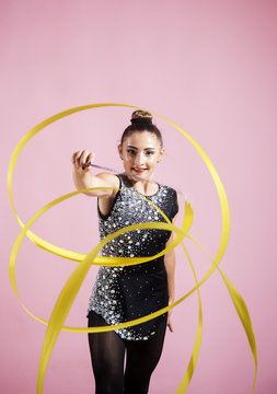 Beautiful happy cool fit gymnast athlete woman in sportswear working out, doing rhythmic gymnastics exercise Spirals with art ribbon and dancing.