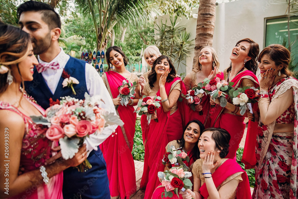 Wall mural Bridesmaids stand around gorgeous Indian wedding couple