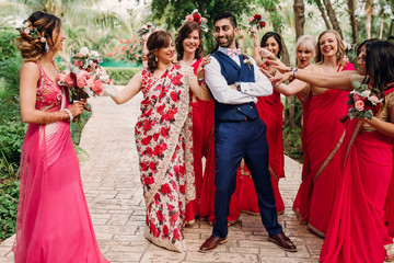 Fototapeta na wymiar Funny scenes with bridesmaids trying to keep Hindu bride away from groom