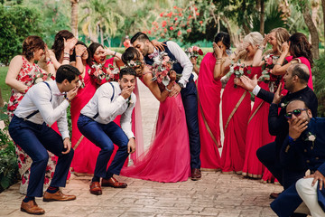 Friends admire newlyweds while they kiss in the garden - Powered by Adobe