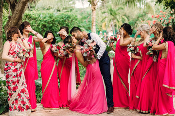 Bridesmaids stand around gorgeous Indian wedding couple