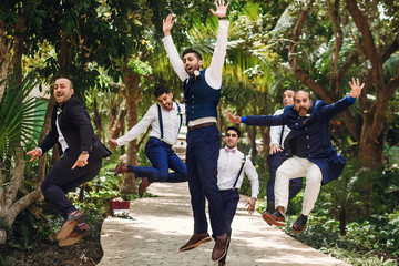 Hindu groom and groomsmen have fun jumping outside in the garden