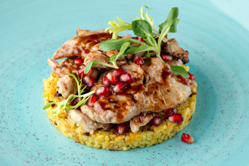 Closeup view of meat with bulgur, pomegranate and fresh vendure on turquoise plate