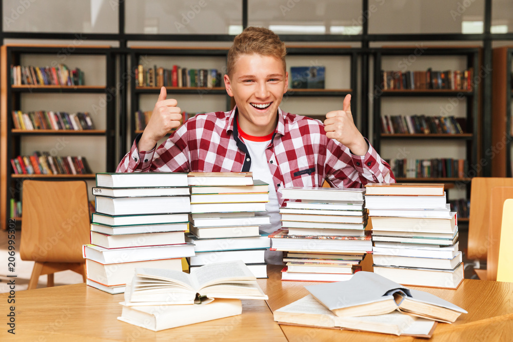 Sticker Smiling teenage boy sitting at the library table