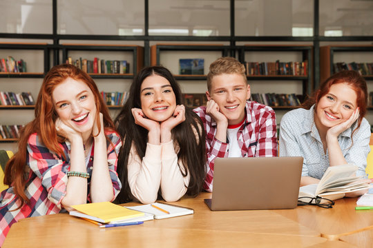 Group of smiling teenagers doing homework