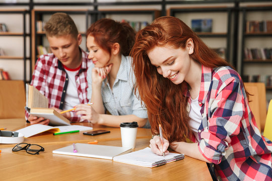 Group of happy teenagers doing homework