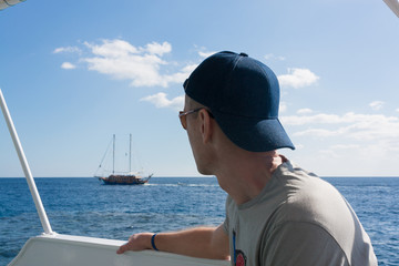 A man sits aboard a yacht and admires the scenery with boat. Blue sea and sky. Recreation and tourism. The concept.