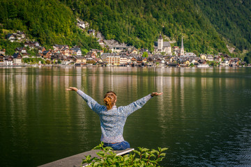girl is sitting on wooden bridge. Young tourist woman sits on the bridge and enjoy the relaxation and freedom. Beautiful view of the mountain nature. wonderful view of Hallstatt. 
