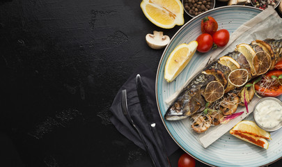 Fried fish with vegetables served at restaurant on black table