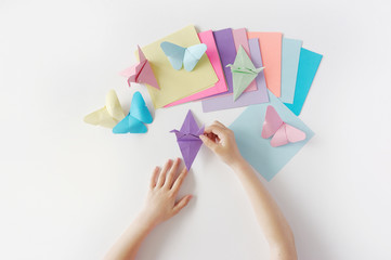 Children's hands do origami from colored paper on white background. lesson of origami