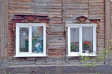 Two windows in an old wooden house decorated with wooden carvings