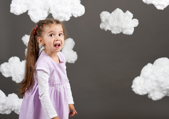 girl playing with clouds, shooting in the studio on a gray background, happy childhood concept