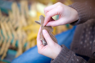 Close up fingers of young woman sitting in autumn forest and sewing something